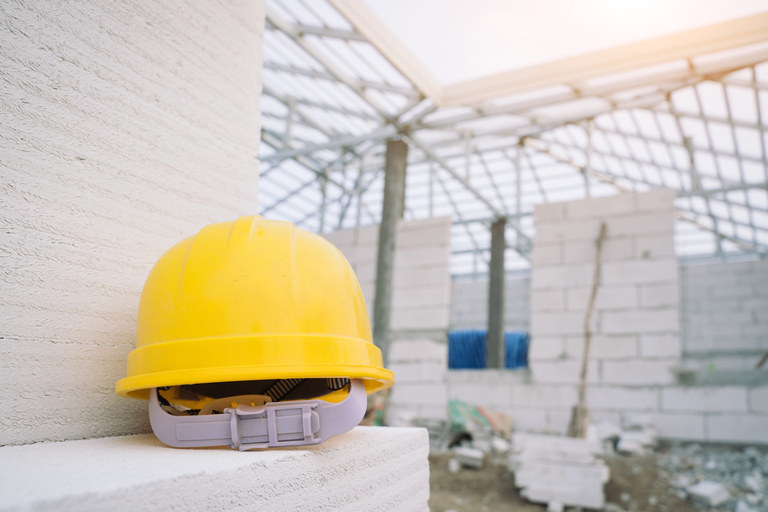 A yellow hard hat placed on top of a white concrete brick in a construction site