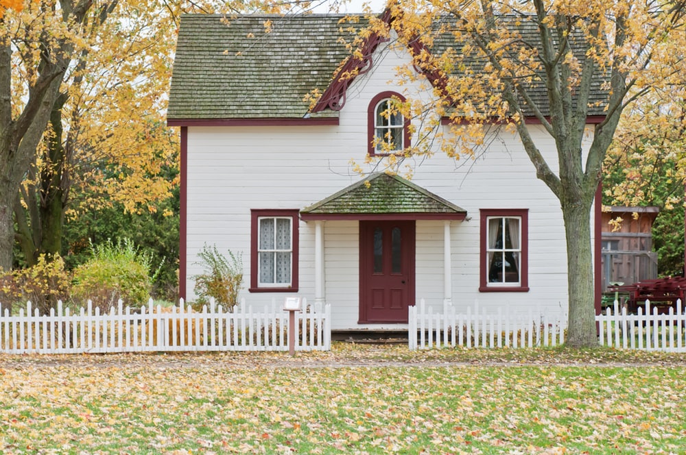 A white house behind a white fence during Autumn