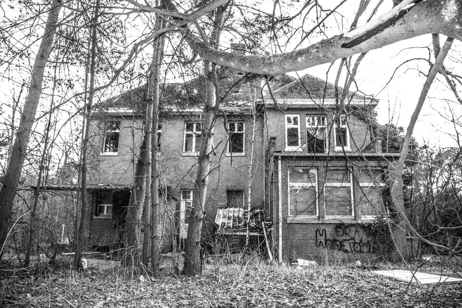 Black and white photo of an abandoned building in a wooded area