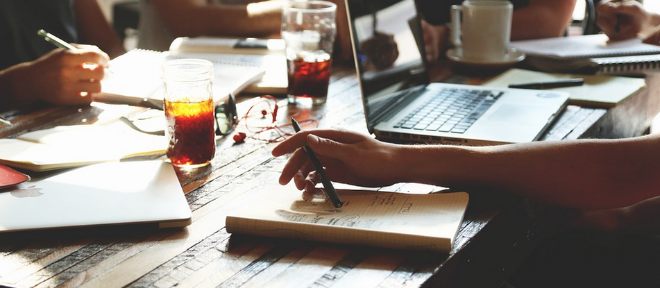 A restaurant table surrounded by people working on paper and laptops