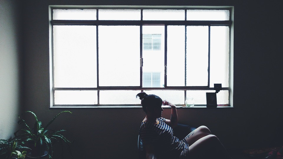 A person sat infront of a large window with light shining through