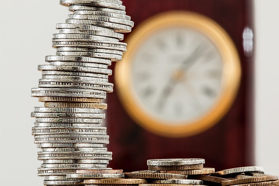 Coins stacked in front of a blurry clock