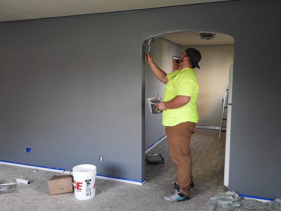 Person in yellow shirt painting a grey archway