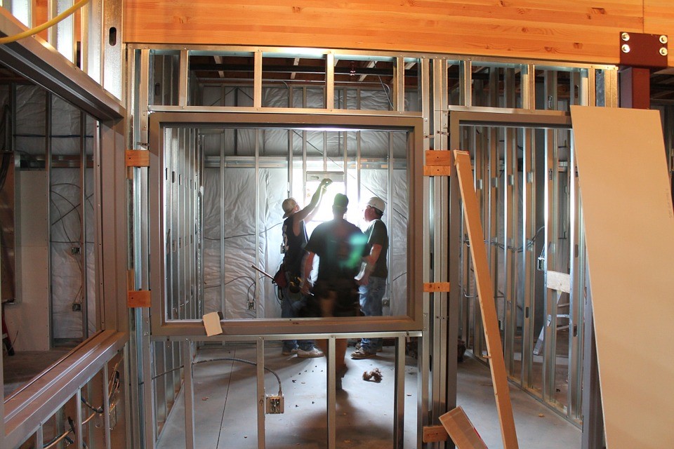 Inside view of a house skeleton with workers surveying