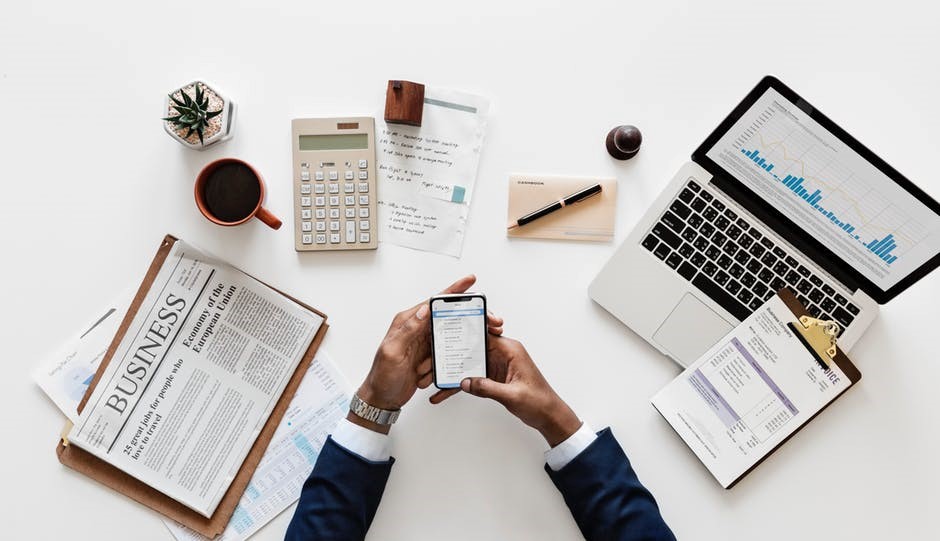 Person holding iPhone surrounded by other office accessories